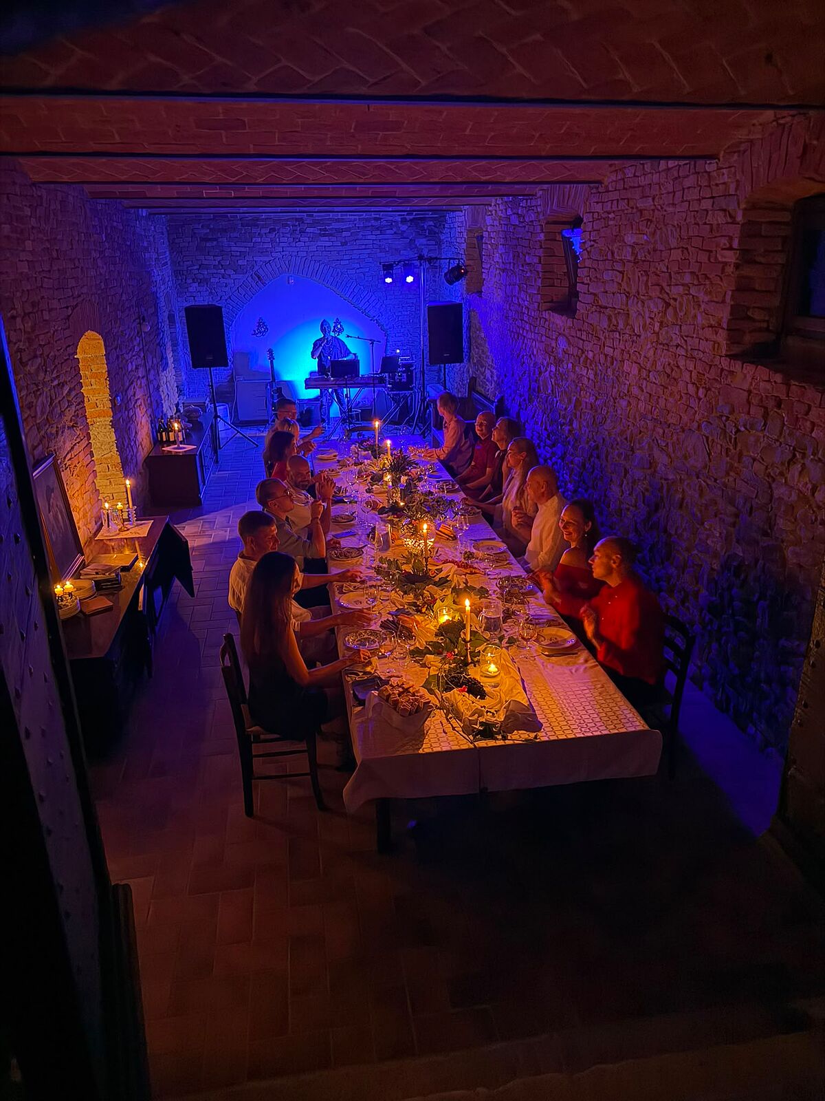 Een diner bij kaarslicht voor een groep in de gewelfde cantina van Cascina Blon